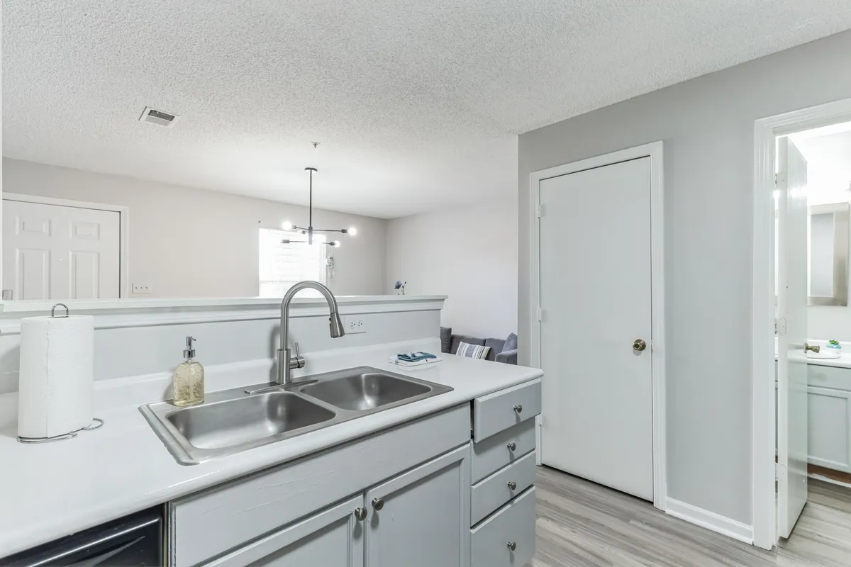 A welcoming apartment kitchen featuring a bright countertop, a stylish sink, and open doorways that subtly suggest access to the broader living space. The scene is set for morning coffee rituals or preparing a meal before heading out to explore Fayetteville.